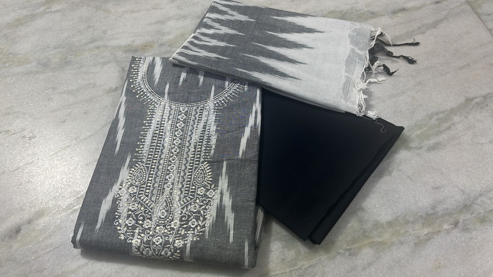 Gray patterned fabric with white embroidery on a marble surface